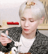 a young man with white hair is eating a piece of cake