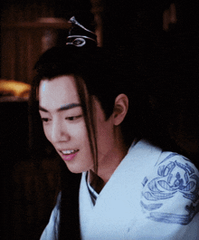 a young man with long hair wearing a white shirt with a blue floral design on the shoulder