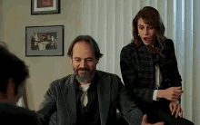 a man and a woman are sitting next to each other in front of a window