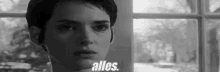 a black and white photo of a woman looking out of a window with the words alles .