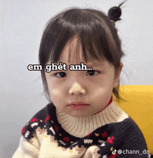 a little girl is wearing a sweater and making a funny face