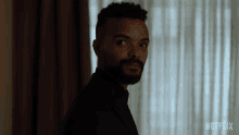 a man with a beard is standing in front of a curtain with netflix written on the bottom