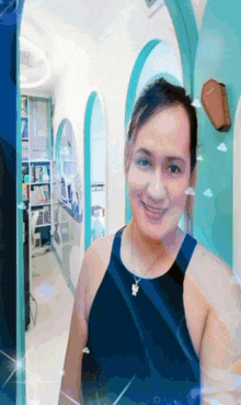 a woman in a black tank top is smiling in a room