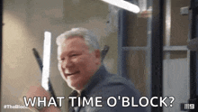 a man is holding a light and smiling while asking what time o ' block ?