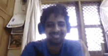 a man is wearing headphones and smiling while sitting in front of a window .