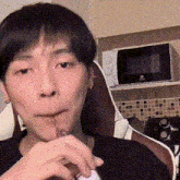 a man is drinking from a bottle with a straw in a kitchen .