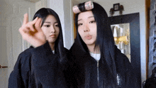 two girls are standing next to each other in front of a mirror and one of them is making a funny face .