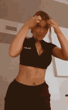 a woman wearing a black crop top that says ' waj ' on it