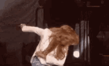 a woman is dancing on a stage in a dark room .