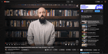 a man with a beard is standing in front of a shelf of books on youtube