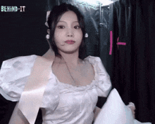a woman in a white dress is holding a piece of paper with the words behind it written on it