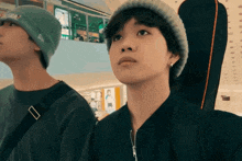 a man wearing a beanie and a black jacket looks up