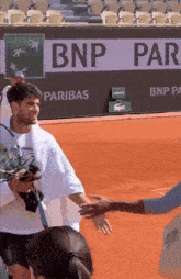 a man shakes hands with another man in front of a bnp pariba banner