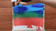 a person is painting a painting with a brush on a wooden table .