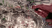 a woman is pouring champagne into a pyramid of champagne glasses .