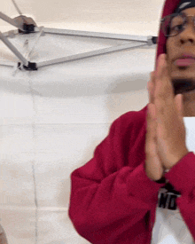 a man wearing glasses and a red hoodie is clapping