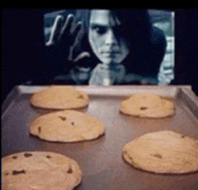 a tray of cookies is sitting in front of a screen with a man 's face on it .