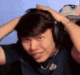 a man wearing headphones is making a funny face with his hands on his head