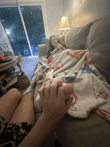 a couple holding hands on a couch with a blanket on it