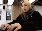 a young man with blonde hair is typing on a laptop computer .