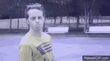 a man in a yellow shirt with an american flag on it is standing on a street .