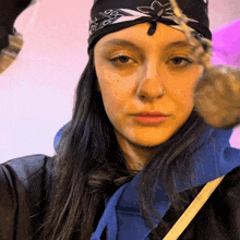 a woman wearing a bandana and a nose ring looks at the camera