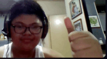 a young boy wearing headphones and glasses is giving a thumbs up
