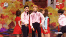 a group of people dancing in front of a screen that says ' mnet ' on it