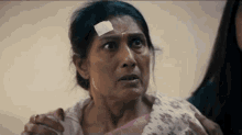 a woman with a bandage on her forehead is being comforted by a woman .