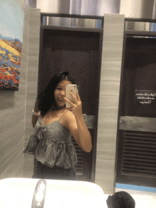a woman taking a picture of herself in a bathroom with a sign that says no smoking
