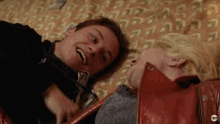 a man and a woman are laying next to each other on a bed and smiling .