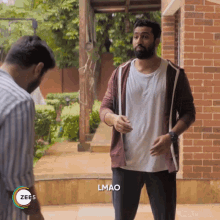 a man with a beard is standing in front of a brick wall with the words lmao on the bottom