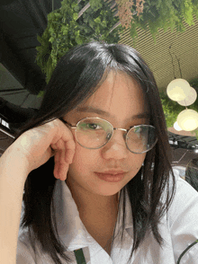 a young woman wearing glasses and a white shirt looks at the camera