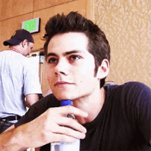 a young man is sitting at a table holding a bottle of water