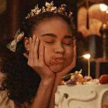 a girl with a tiara on her head is making a funny face in front of a cake