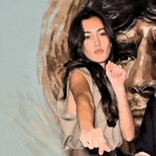 a woman with a ring on her finger is standing in front of a painting