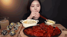 a woman is eating food with chopsticks and a bowl of food in the background