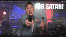 a video of a man holding a microphone with the caption " for satan "