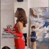 a woman in a red dress is standing next to a boy in a blue shirt .