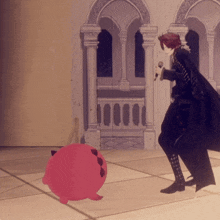 a man in a black cape is singing into a microphone while standing next to a pink toy