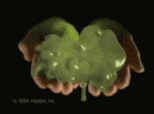 a close up of a person 's hands holding a green substance that says 1996 hasbro inc.