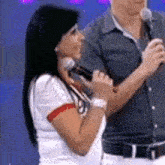 a woman is holding a microphone while standing next to a man holding a microphone .