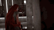 a woman with long red hair is standing next to a pillar .