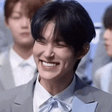 a young man in a suit and bow tie is smiling .