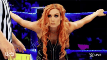 a woman with red hair is standing in a wrestling ring .