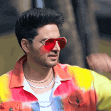 a man wearing red sunglasses and a tie dye shirt that says happy insane