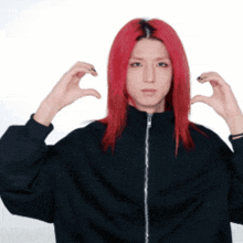 a woman with red hair is making a heart with her hands