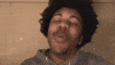 a man with curly hair is making a funny face with his eyes closed and his mouth open .