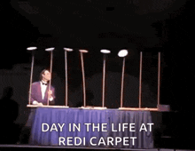 a man in a tuxedo is performing a trick on a stage while holding a hammer .