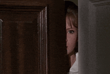 a woman peeking out of a door with her eyes closed